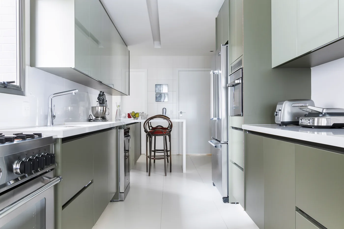 Cozinha do Apartamento Alto de Pinheiros com marcenaria verde suave e bancada branca