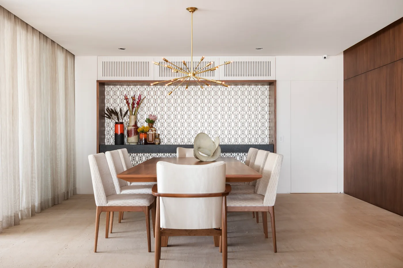 Sala de jantar com mesa de madeira, cadeiras claras e painel branco com textura