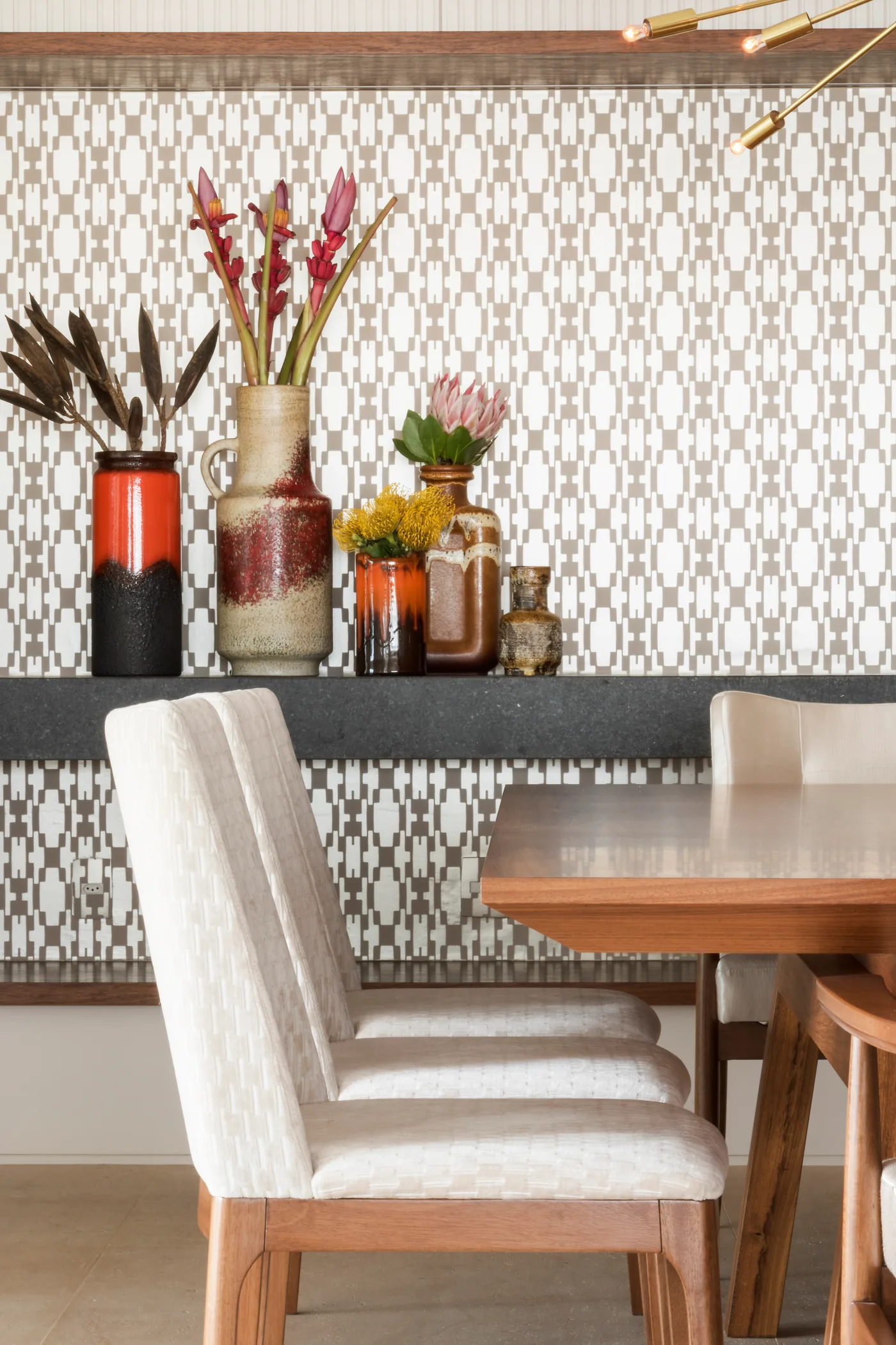 Detalhe da sala de jantar com vasos, flores e revestimento geométrico