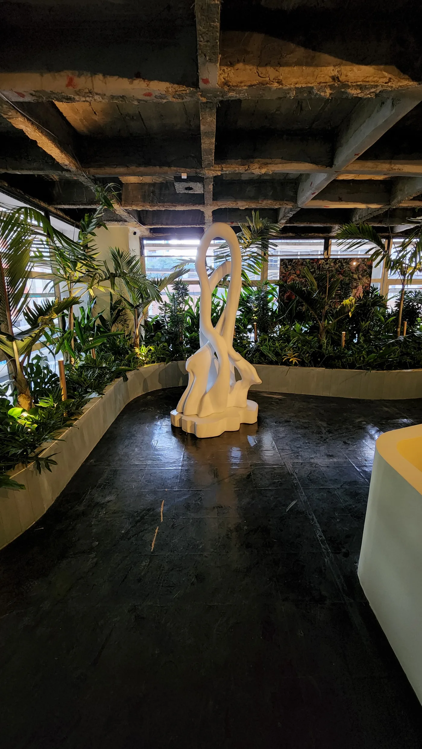 Corredor do Restaurante Tropical com escultura branca, piso escuro e jardim interno