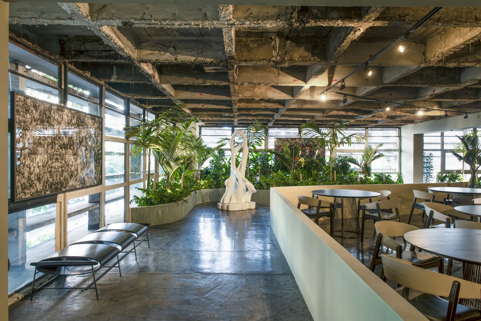 Restaurante Tropical do CASACOR BADEBEC com vegetação exuberante, escultura branca e teto de concreto aparente