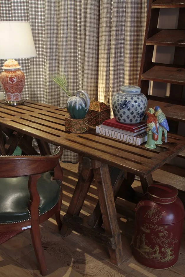 Aparador de madeira com luminária, vasos azuis, objetos coloridos e cortina xadrez