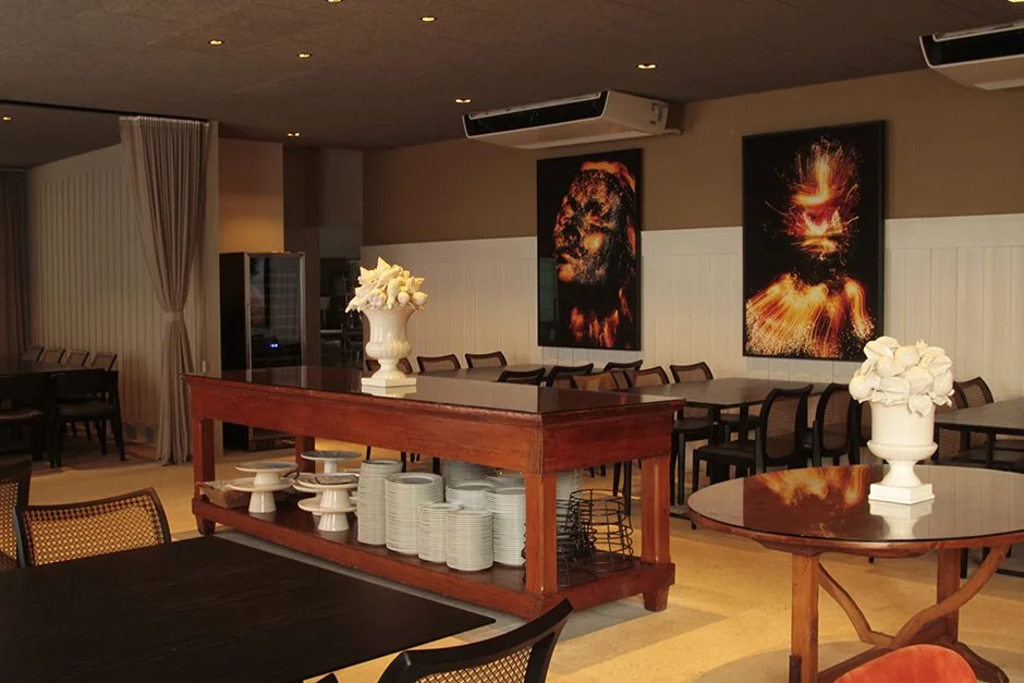 Buffet central de madeira com louças brancas e obras de arte no restaurante BADEBEC