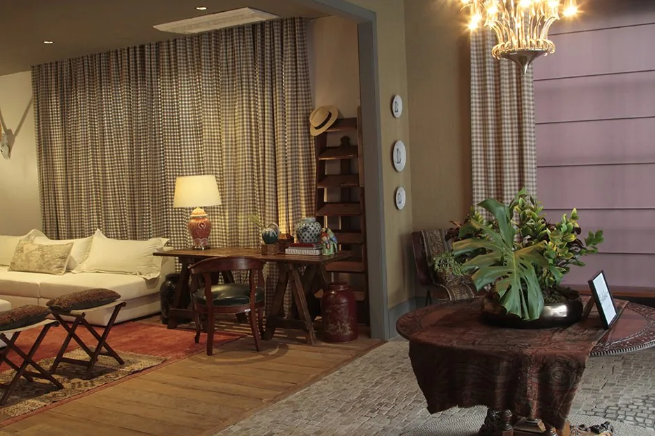 Entrada do ambiente com lustre, mesa redonda, plantas e vista para o estar com sofá branco