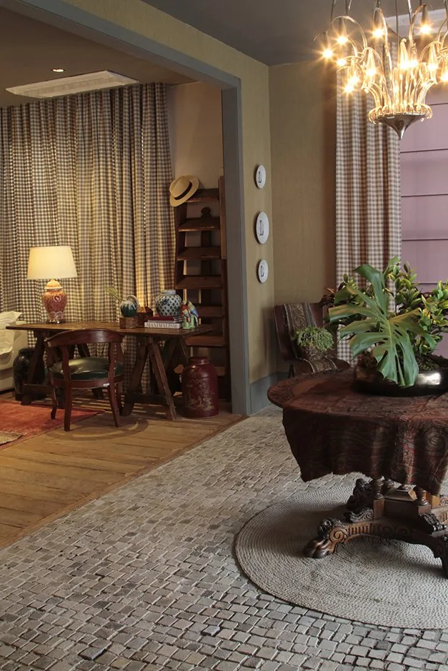 Entrada do CASACOR BADEBEC com lustre, mesa decorativa e ambiente de estar ao fundo