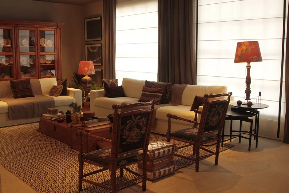 Living com sofás brancos, cristaleira de madeira, poltronas antigas e luminárias de mesa