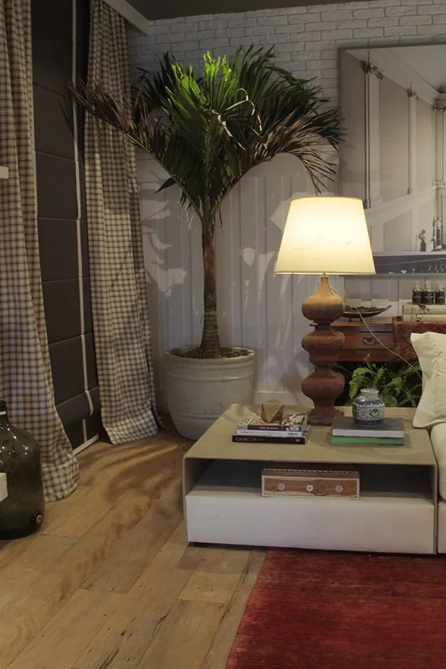 Mesa lateral com livros e luminária ao lado de palmeira no living do restaurante