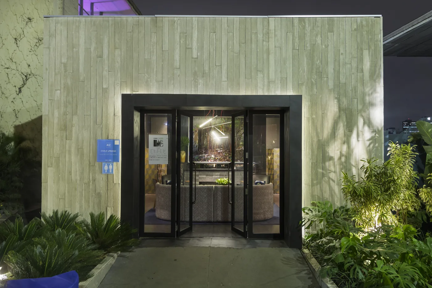 Fachada iluminada do CASACOR Chalé Urbano com paisagismo