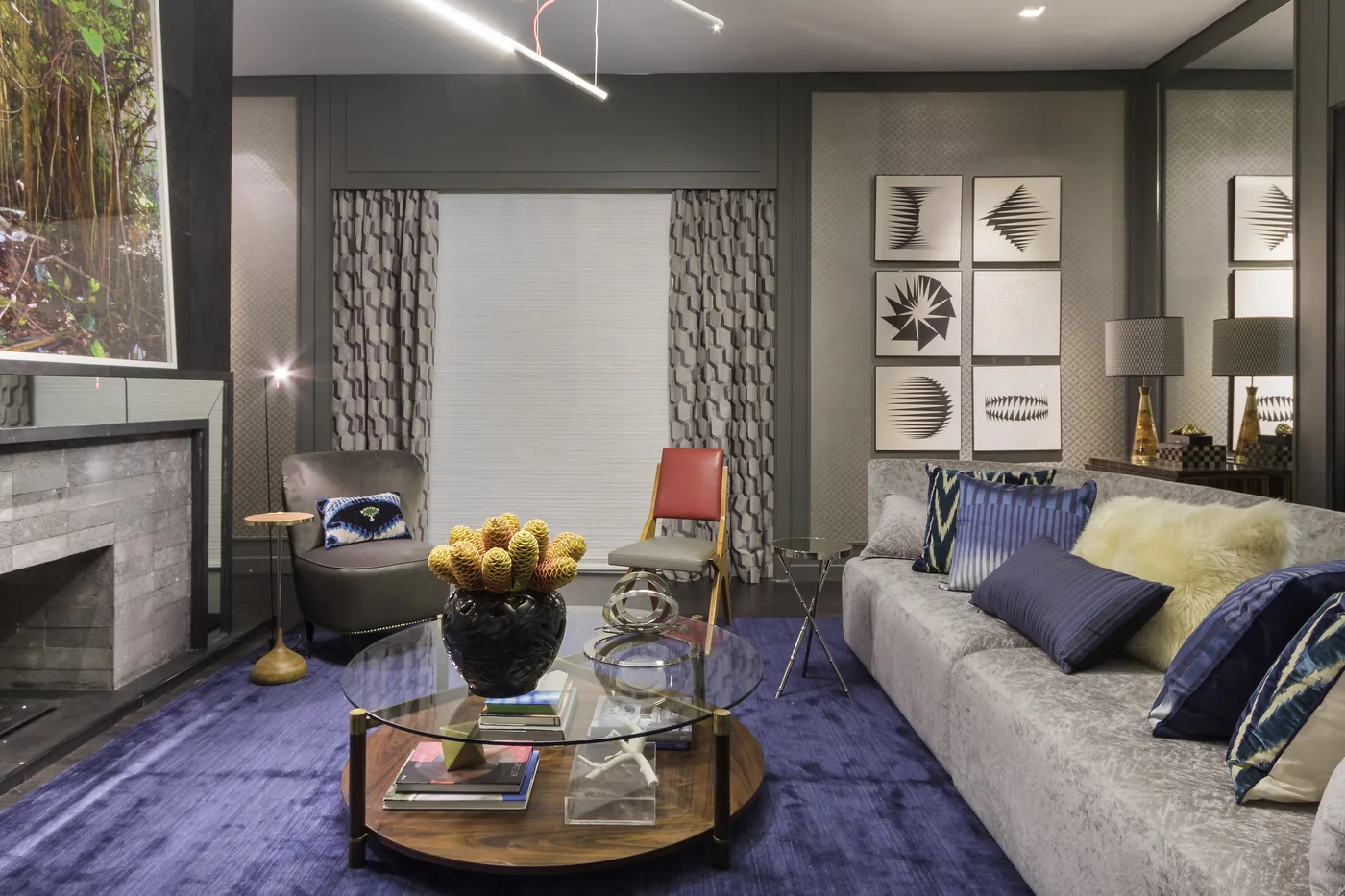 Living do CASACOR Chalé Urbano com sofá curvo, tapete azul e lareira