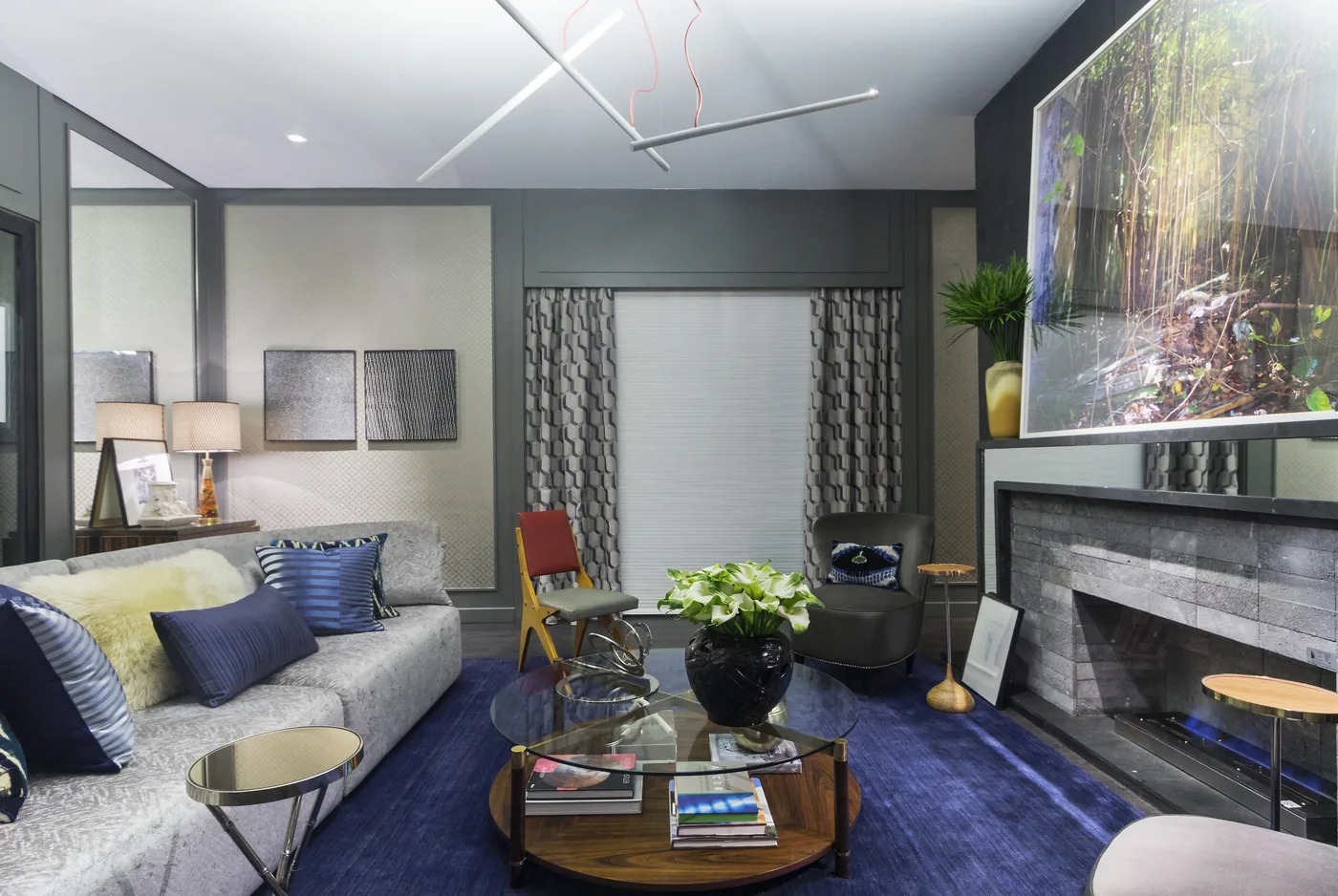 Living com lareira, tapete azul e quadro de vegetação