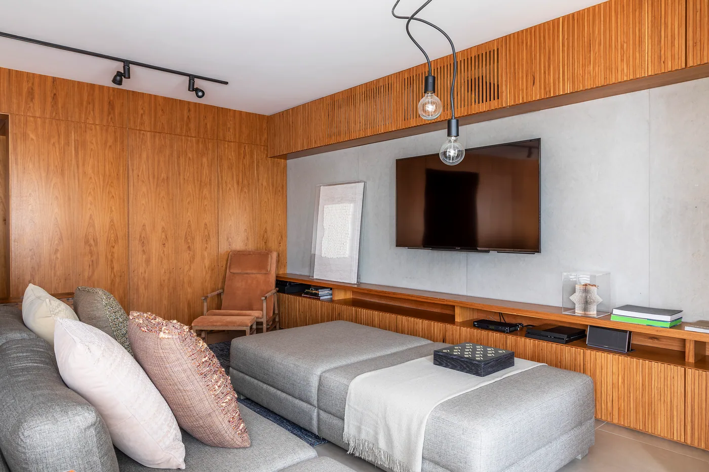 Sala integrada com marcenaria de madeira, sofá e painel de TV