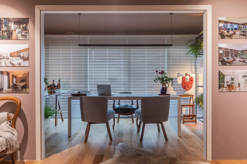 Cadeira em couro verde junto à mesa de reunião e persianas