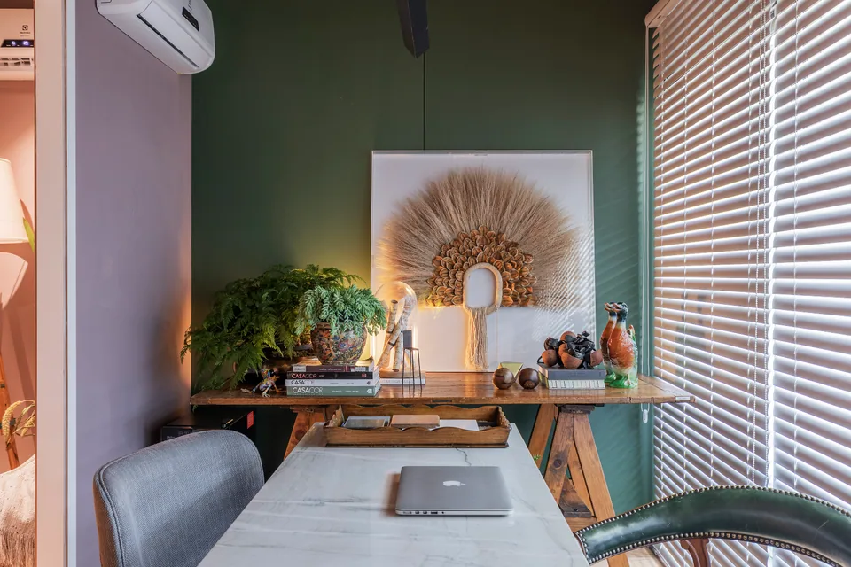 Detalhe da mesa de reunião com livros CASACOR, plantas e objetos decorativos