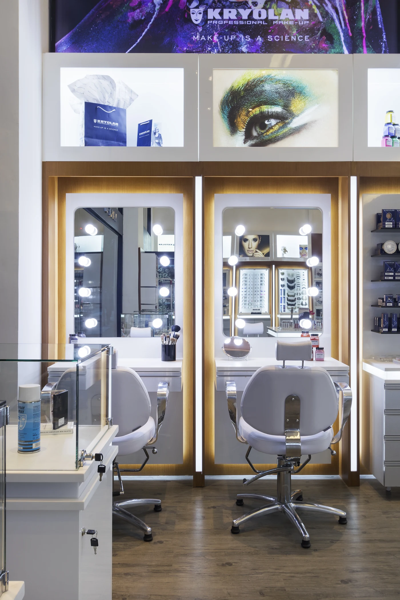 Bancadas de maquiagem da Kryolan Flagship com espelhos iluminados e painel da marca.