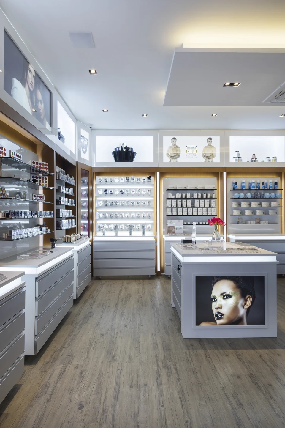 Circulação interna da Kryolan Flagship com displays de produtos, bancada iluminada e acabamento claro.