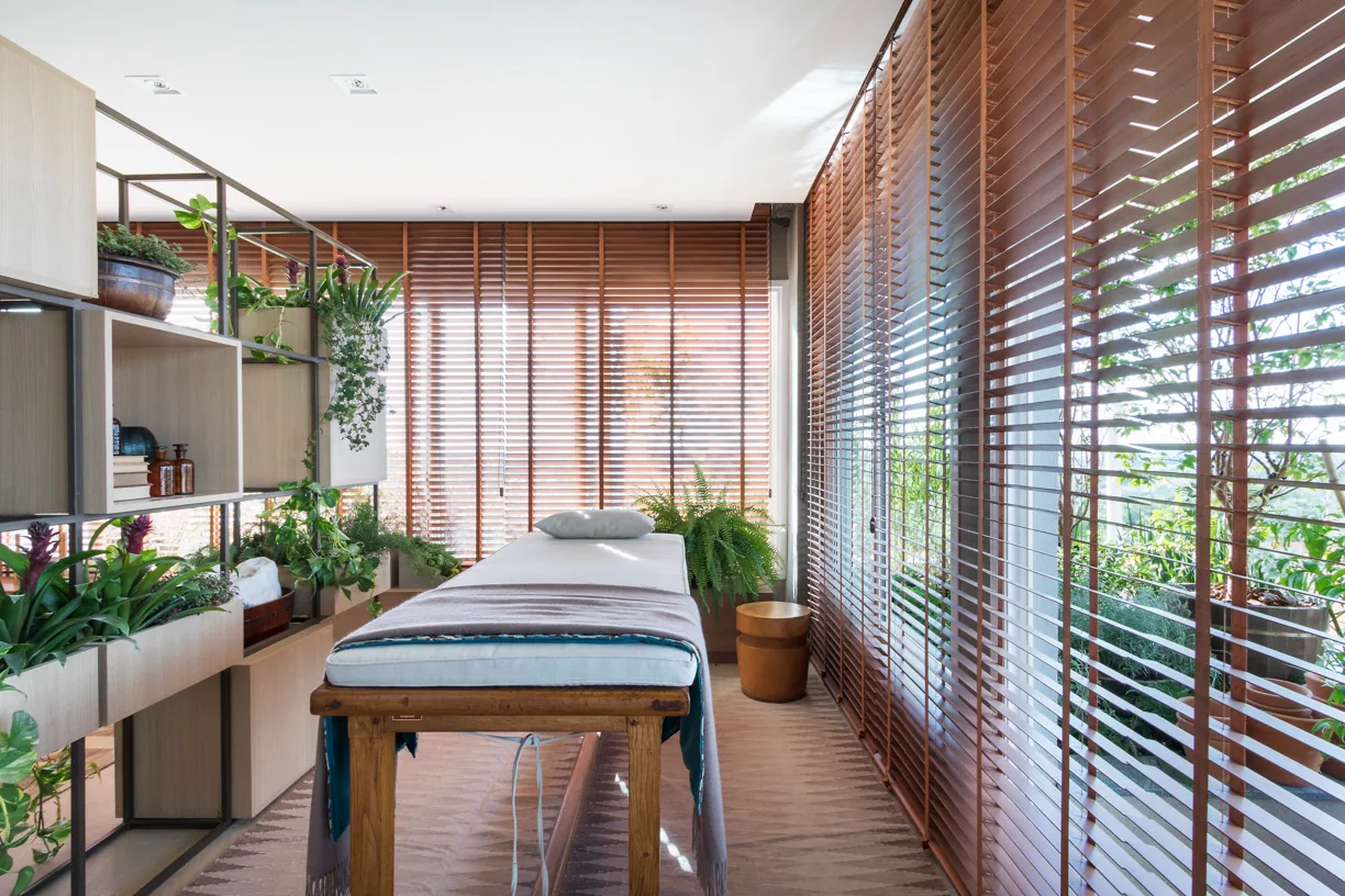 Banheira branca integrada ao ambiente de spa com madeira, plantas e obras geométricas
