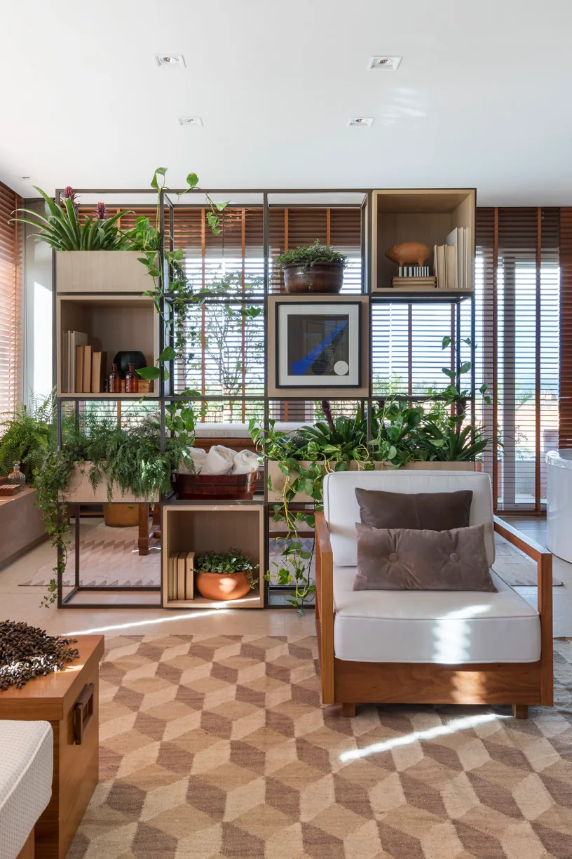 Detalhe das persianas de madeira, almofadas e mesa lateral no ambiente de estar