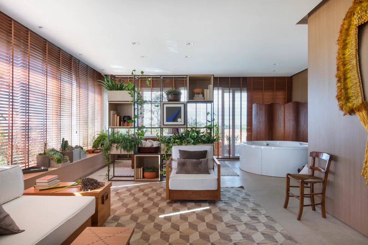 Spa residencial com banheira, poltrona, estante verde e persianas de madeira